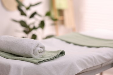 Photo of Rolled towel on massage table in spa center. Space for text