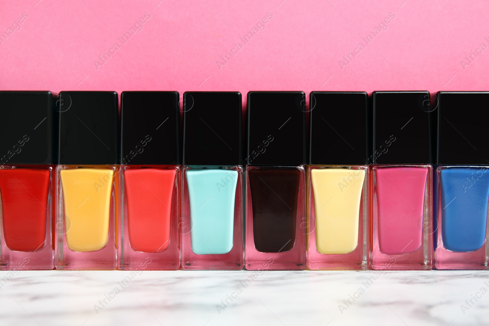 Photo of Bright nail polishes on table against color background