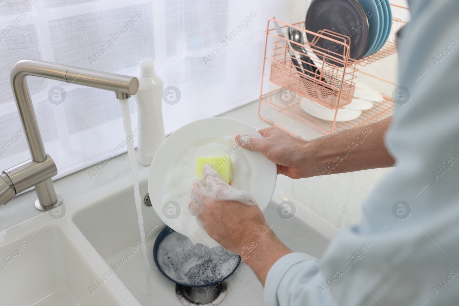 Photo of Man washing plate above sink in kitchen, closeup