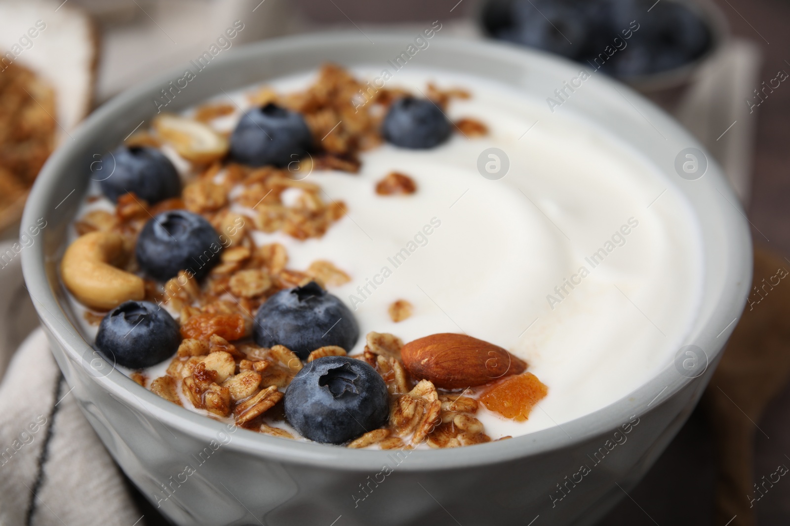 Photo of Bowl with yogurt, blueberries and granola on table, closeup