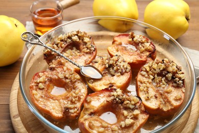 Photo of Tasty baked quinces with walnuts and honey in bowl on table, closeup