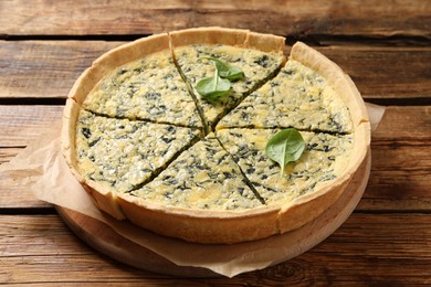 Photo of Cut delicious spinach pie on wooden table