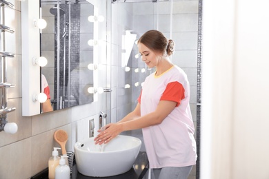 Photo of Young woman washing hands in bathroom. Using soap