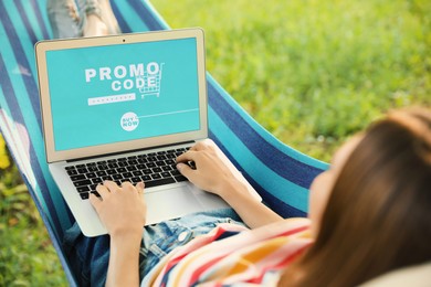 Image of Woman with laptop activating promo code while doing online shopping outdoors