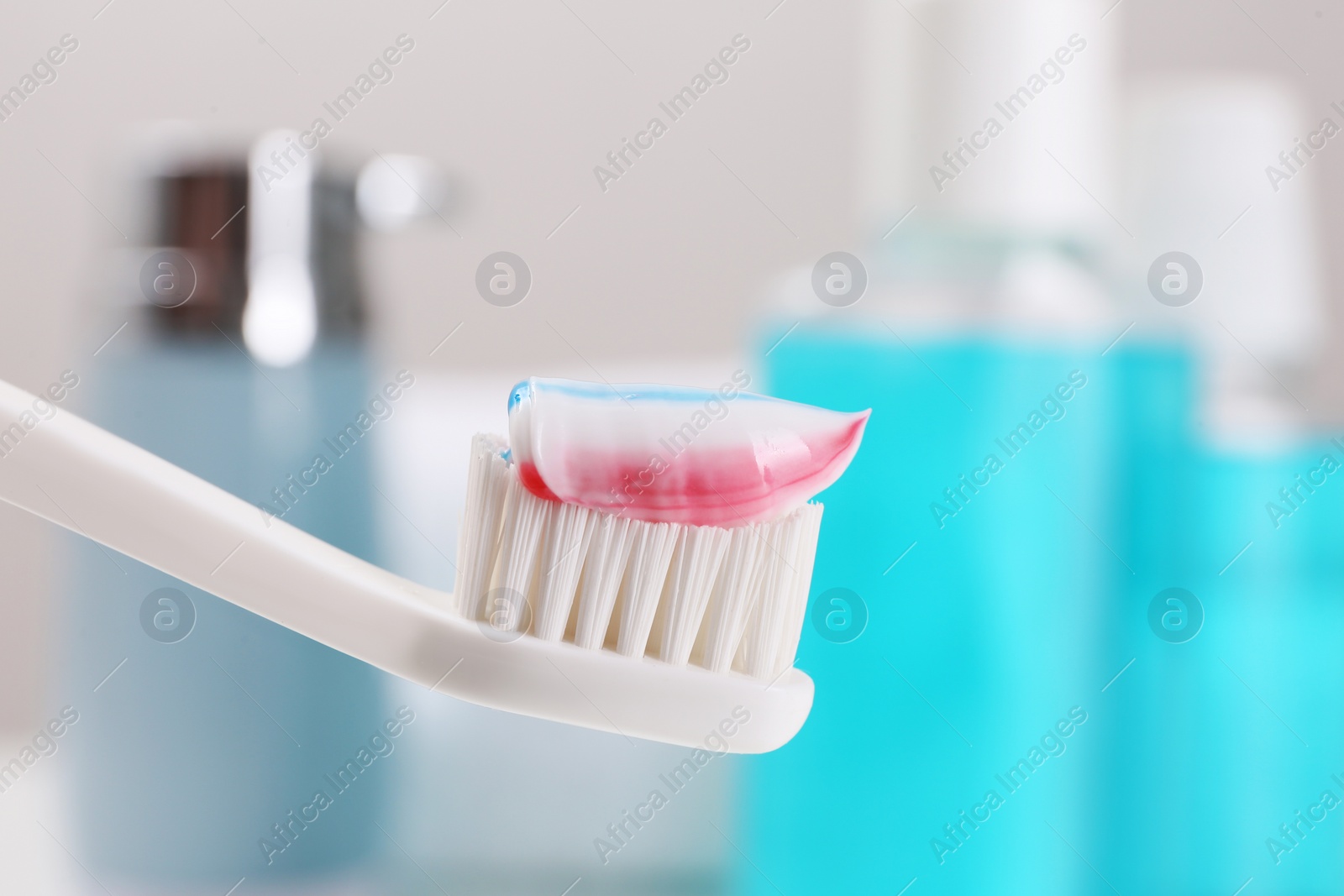 Photo of Toothbrush with paste near mouthwash on blurred background, closeup