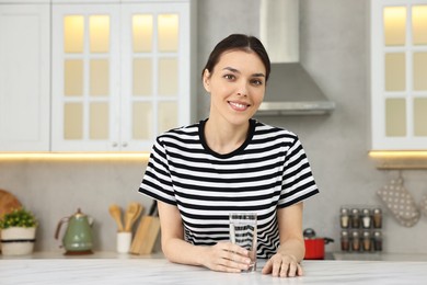 Woman with glass of water at countertop in kitchen