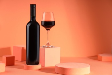 Photo of Stylish presentation of delicious red wine in bottle and glass on orange background. Space for text