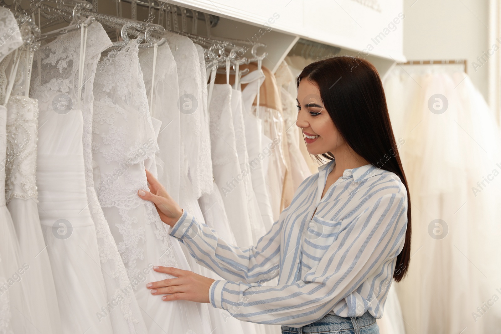 Photo of Young woman choosing wedding dress in salon