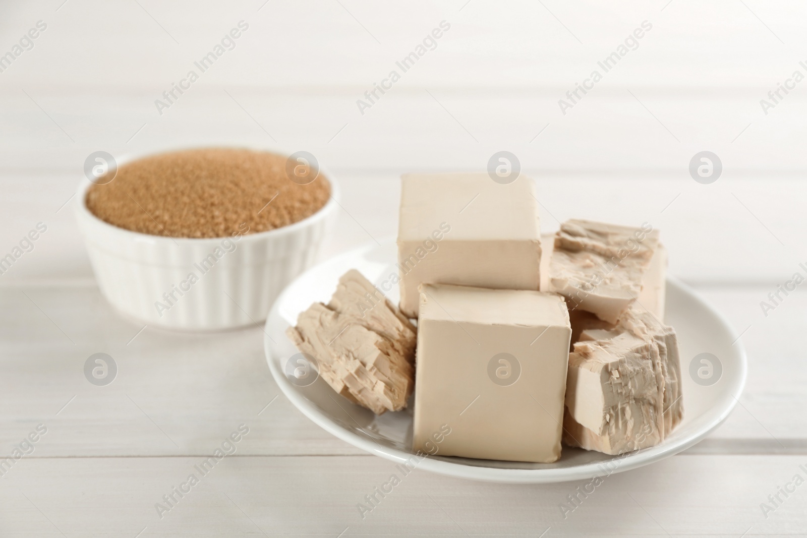 Photo of Compressed and granulated yeast on white wooden table