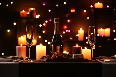 Photo of Romantic dinner table setting with burning candles and festive lights