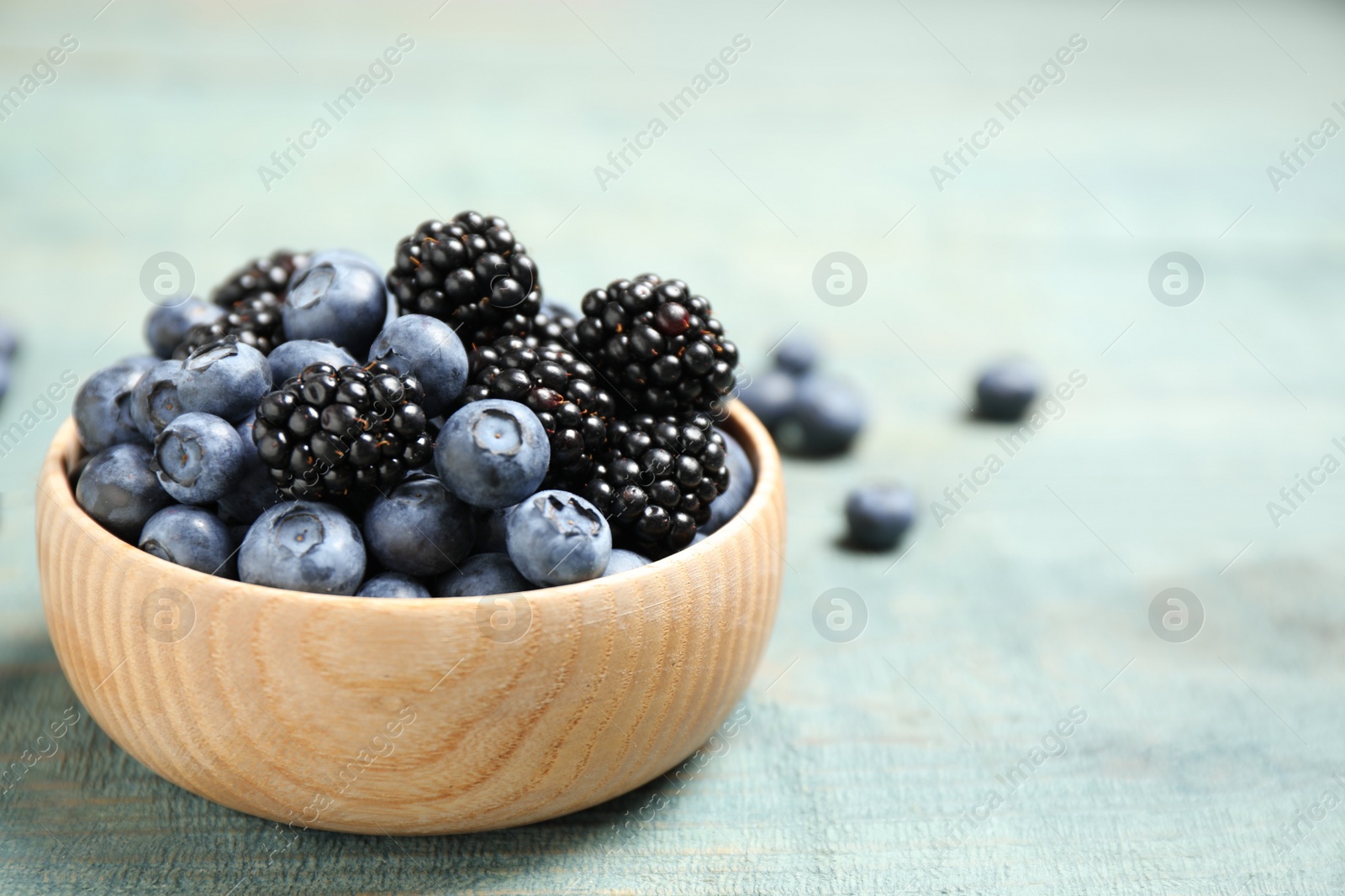 Photo of Blueberries and blackberries on blue wooden table