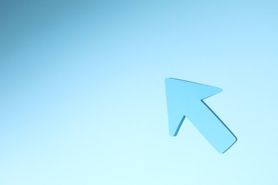 One paper arrow on light blue background, top view. Space for text