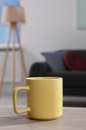 Photo of Yellow mug on wooden table indoors, space for text
