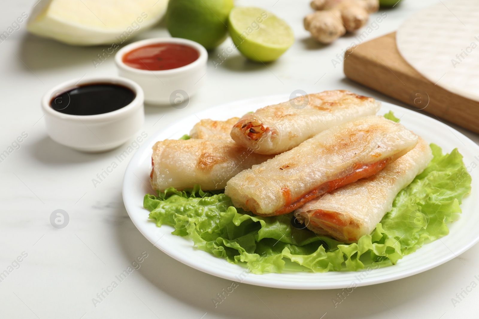 Photo of Delicious fried spring rolls served on white marble table