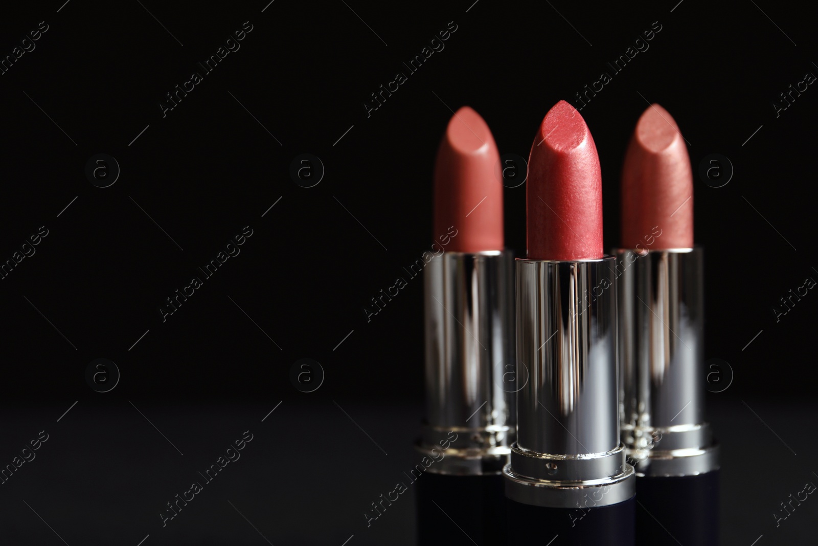 Photo of Different lipsticks on table against dark background. Space for text