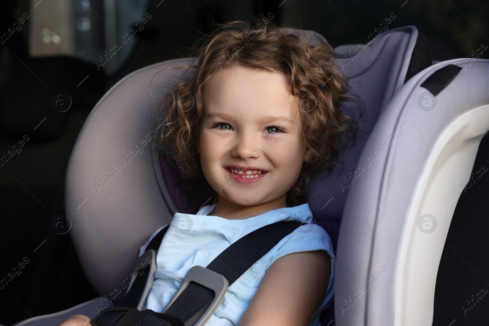 Photo of Cute little girl sitting in child safety seat inside car