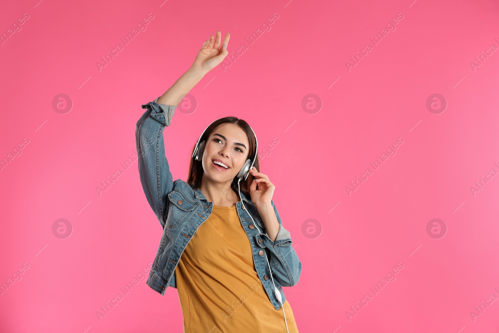 Photo of Beautiful young woman listening to music with headphones on color background. Space for text