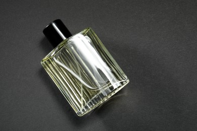 Photo of Luxury men`s perfume in bottle on black background, top view. Space for text