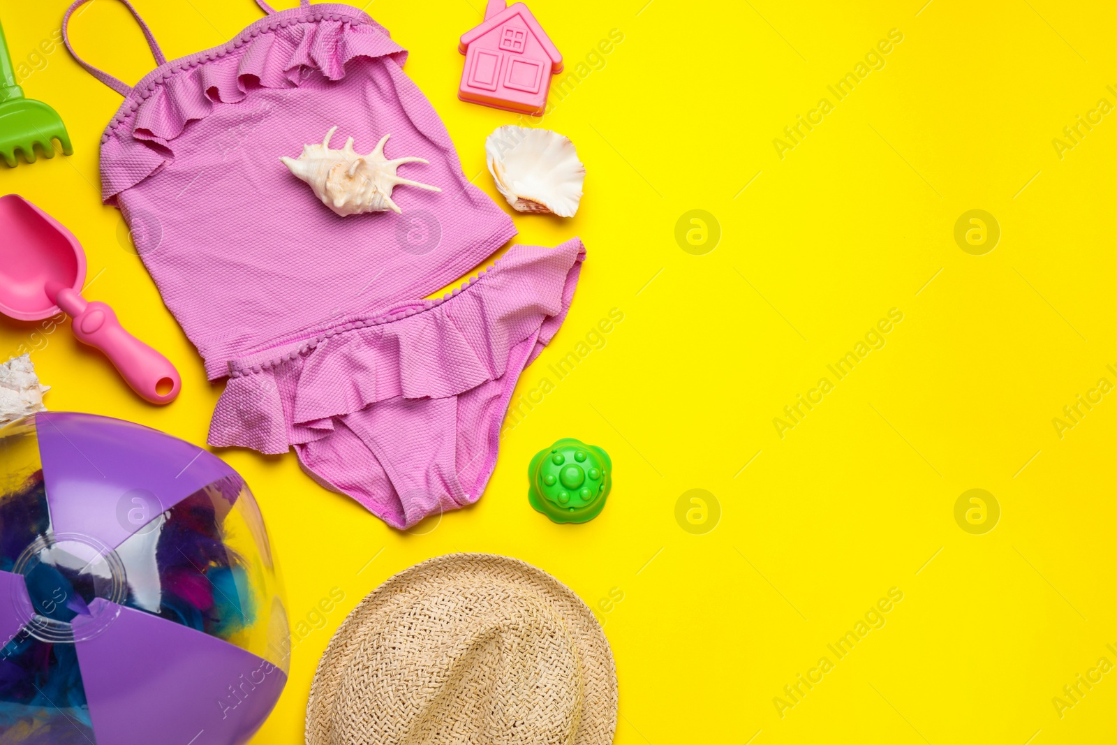 Photo of Flat lay composition with beach ball and sand toys on yellow background, space for text