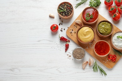 Flat lay composition with different sauces and space for text on white wooden background