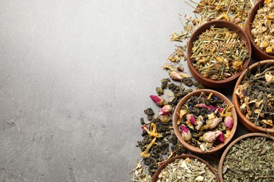 Flat lay composition with different dry teas on grey table, space for text