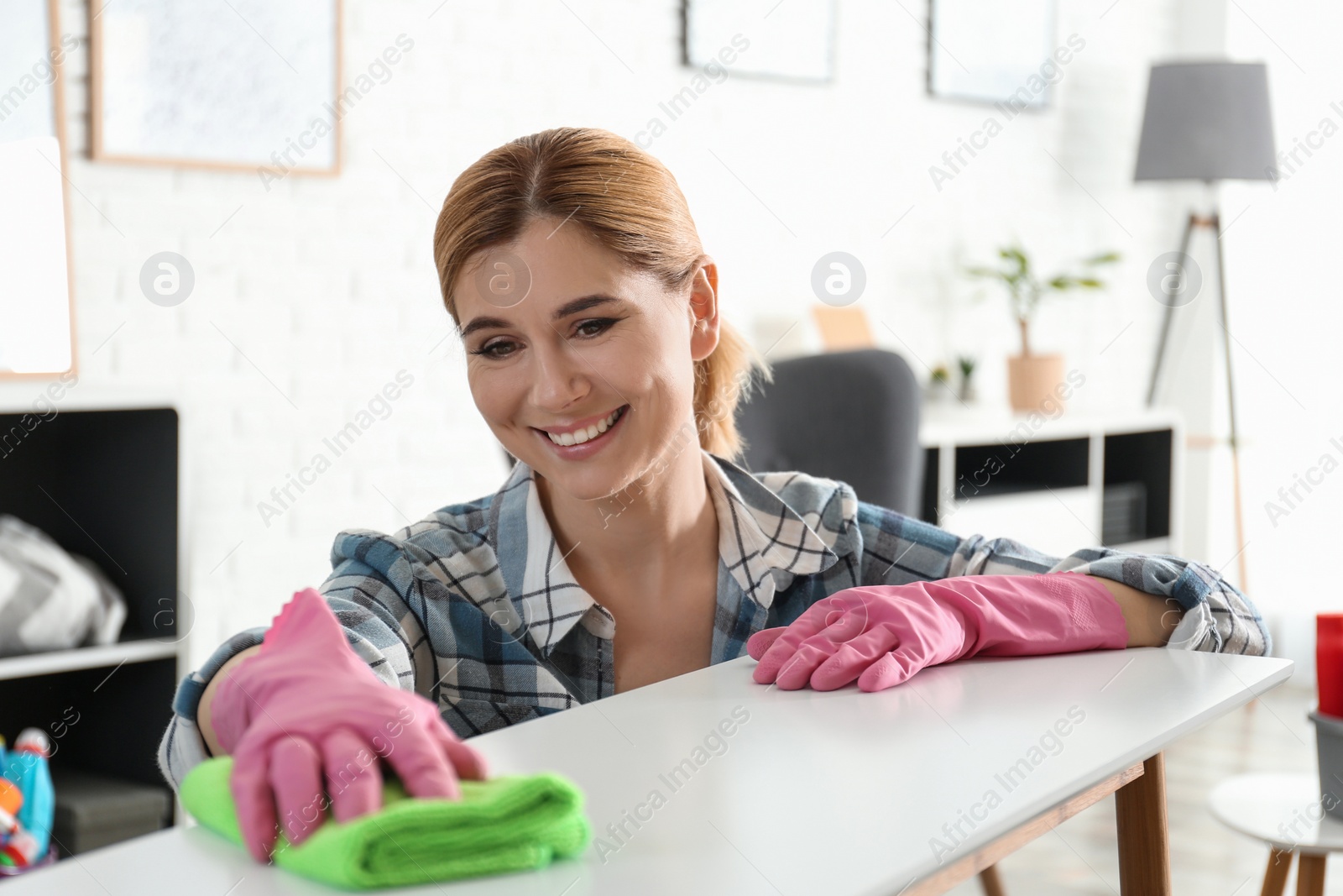 Photo of Portrait of woman cleaning table with rag in living room