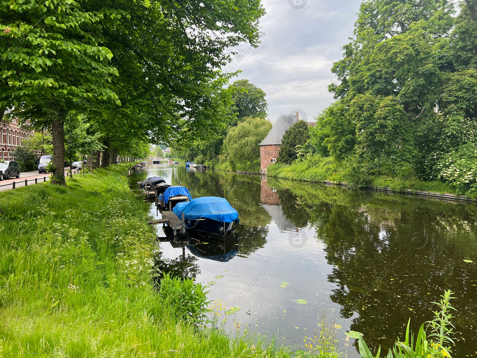 Photo of Beautiful view of city canal with moored boats surrounded by greenery