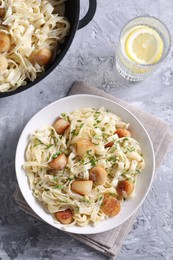 Delicious scallop pasta with spices in dishware on gray textured table, flat lay