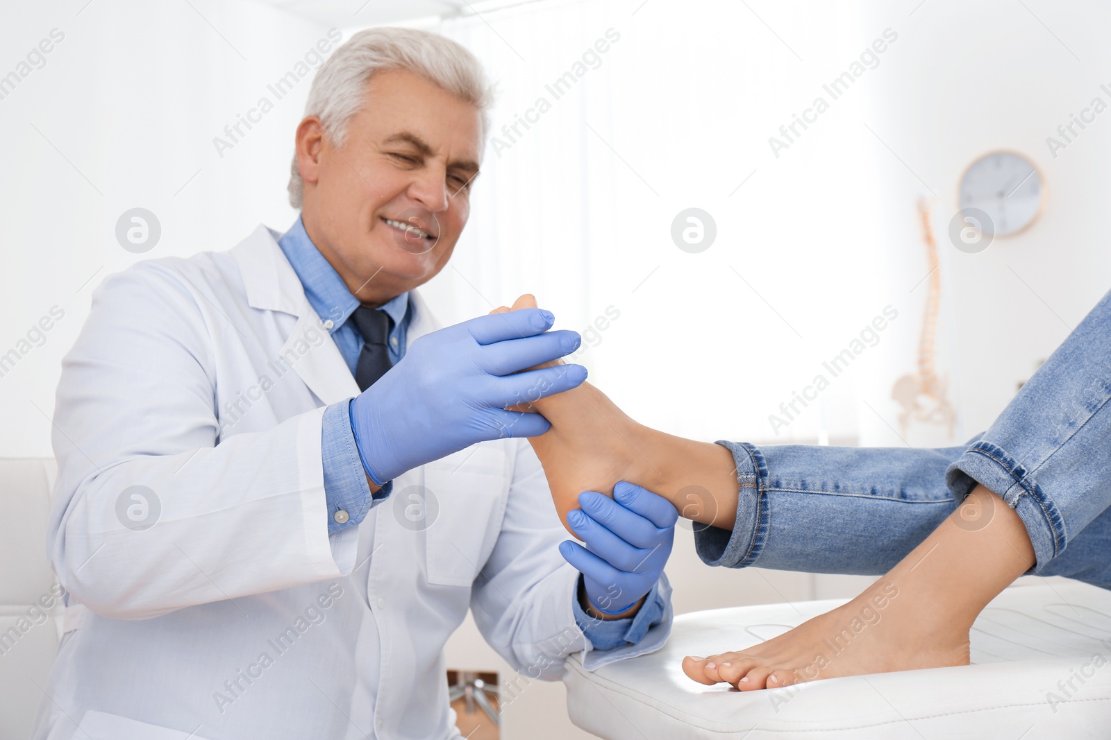 Photo of Male orthopedist checking patient's foot in clinic