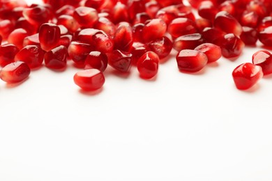 Photo of Many ripe juicy pomegranate grains on white background, closeup. Space for text