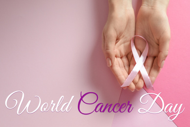 Woman holding pink ribbon on color background, top view. World Cancer Day