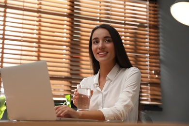 Young woman using laptop for search at wooden table in office