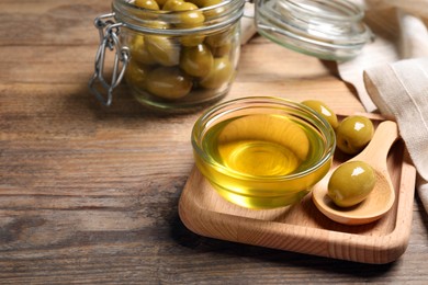 Photo of Bowl of cooking oil and olives on wooden table. Space for text