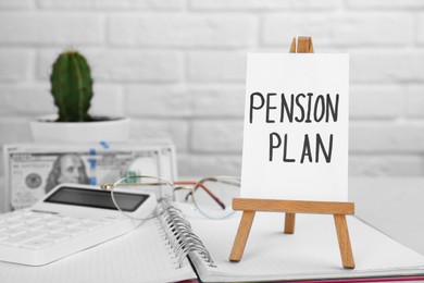 Card with phrase Pension Plan, stationery and money on table