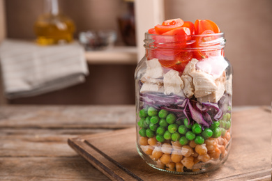 Photo of Healthy salad in glass jar on wooden table. Space for text