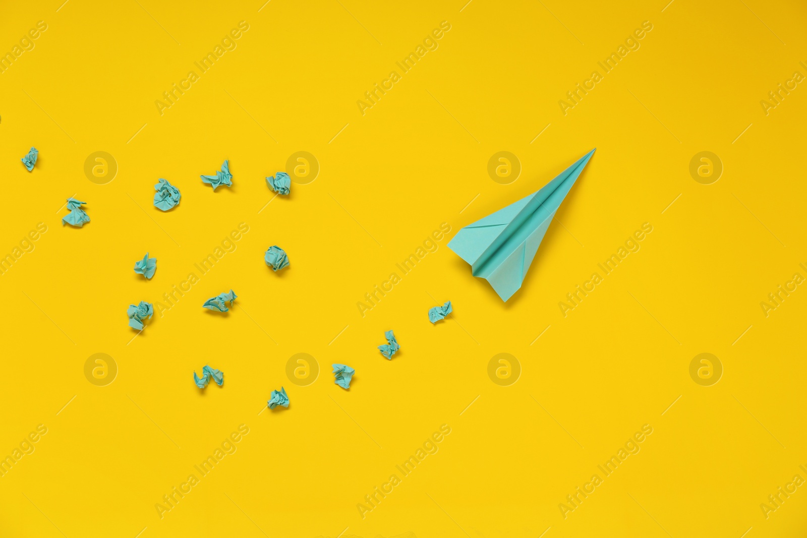 Photo of Handmade plane and many crumpled pieces of paper on yellow background, flat lay