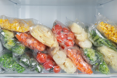 Plastic bags with different frozen vegetables in refrigerator