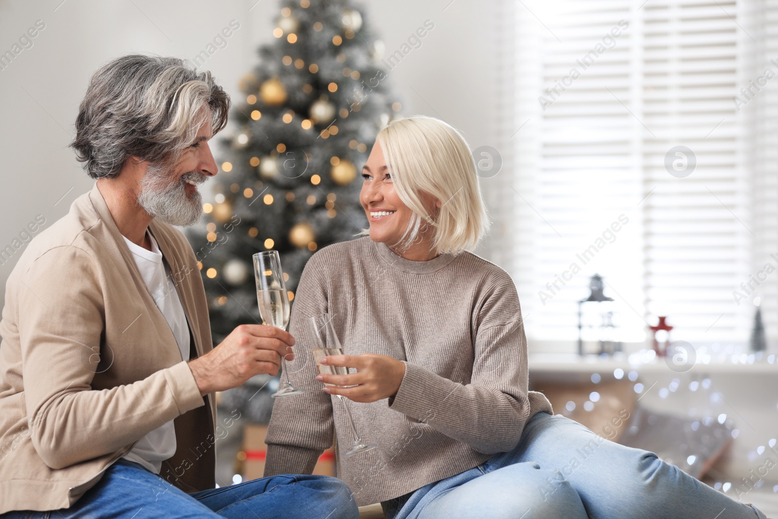 Photo of Happy mature couple with glasses of champagne celebrating Christmas at home