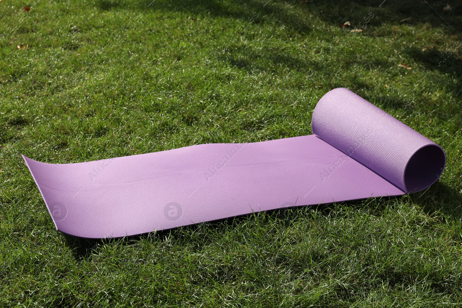 Photo of Bright exercise mat on fresh green grass outdoors