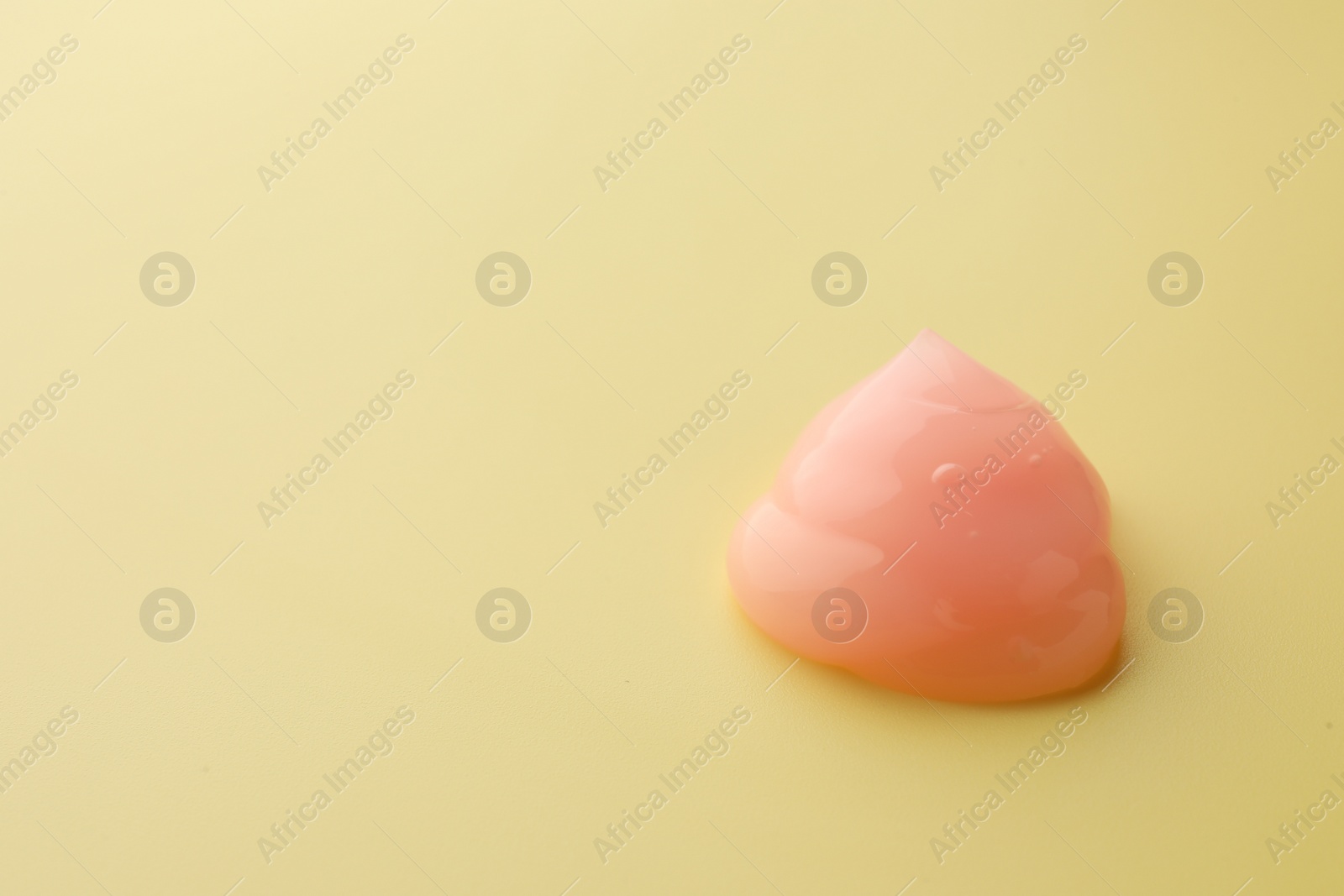 Photo of Sample of pink face cream on yellow background, space for text