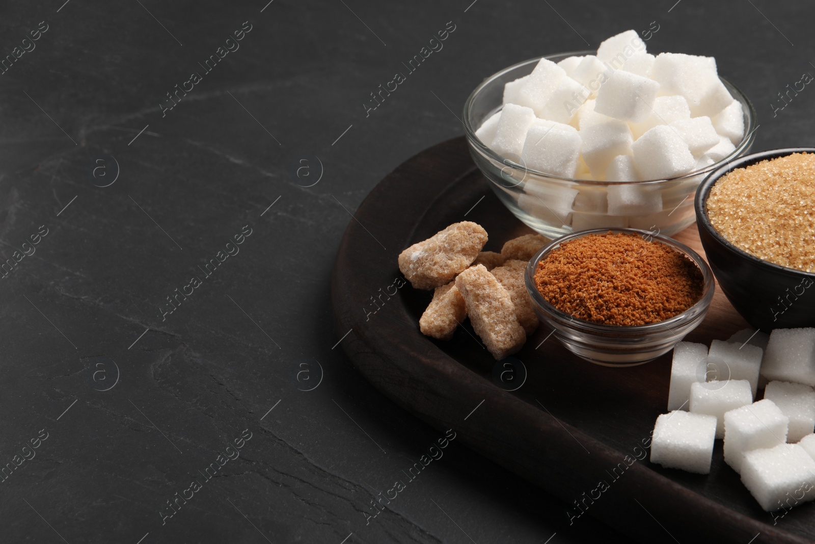 Photo of Different types of sugar on black table, closeup. Space for text