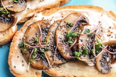 Photo of Tasty toasts with mushrooms, sprouts and chia seeds on color background, closeup