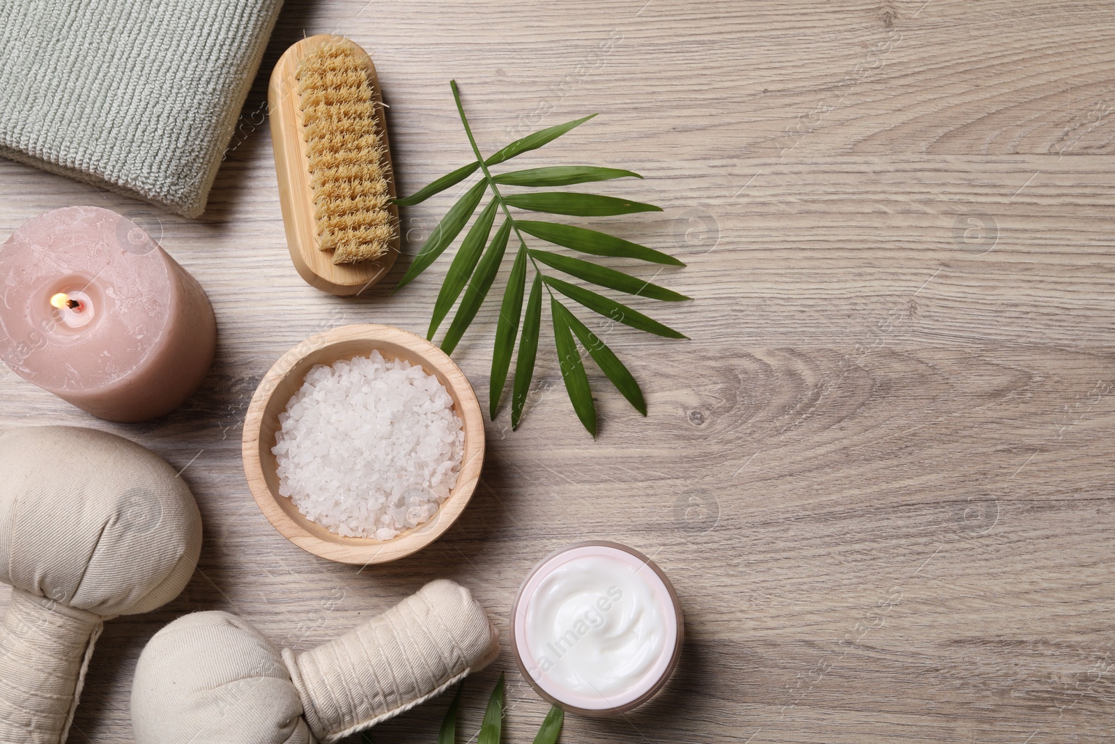 Photo of Flat lay composition with spa products and burning candle on light wooden table. Space for text