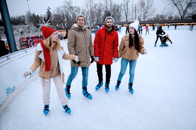 Image of Group of friends skating at outdoor ice rink