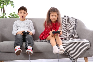 Photo of Emotional children playing video game on sofa in living room