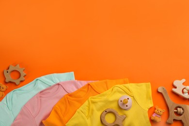 Flat lay composition with baby clothes and accessories on orange background, space for text