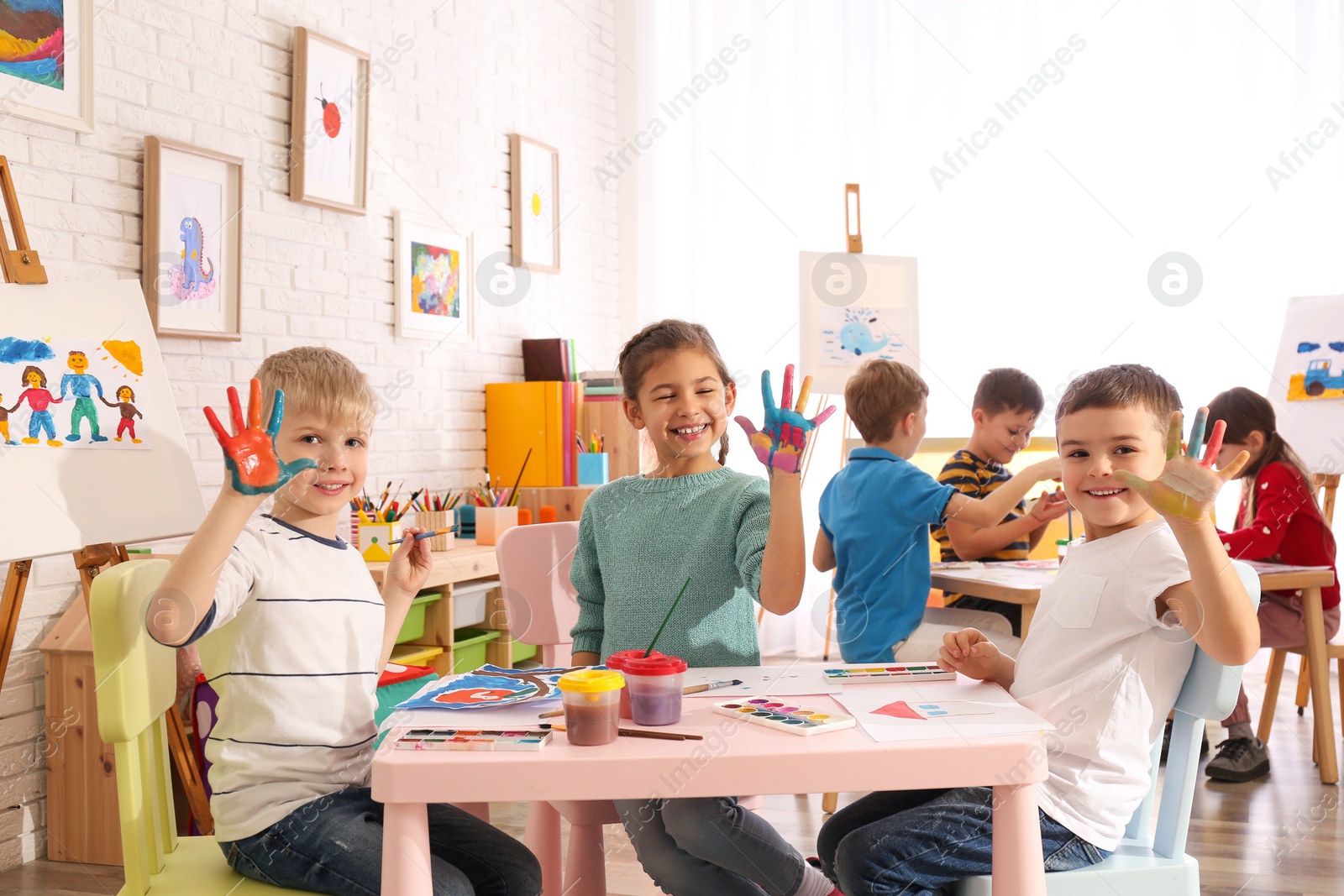 Photo of Cute little children with painted palms in room