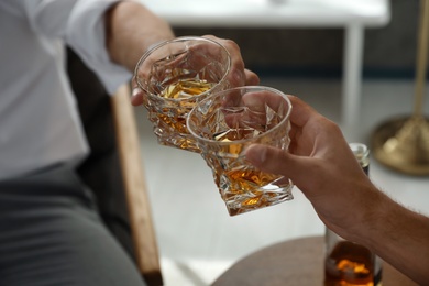 Young men drinking whiskey together at home, closeup