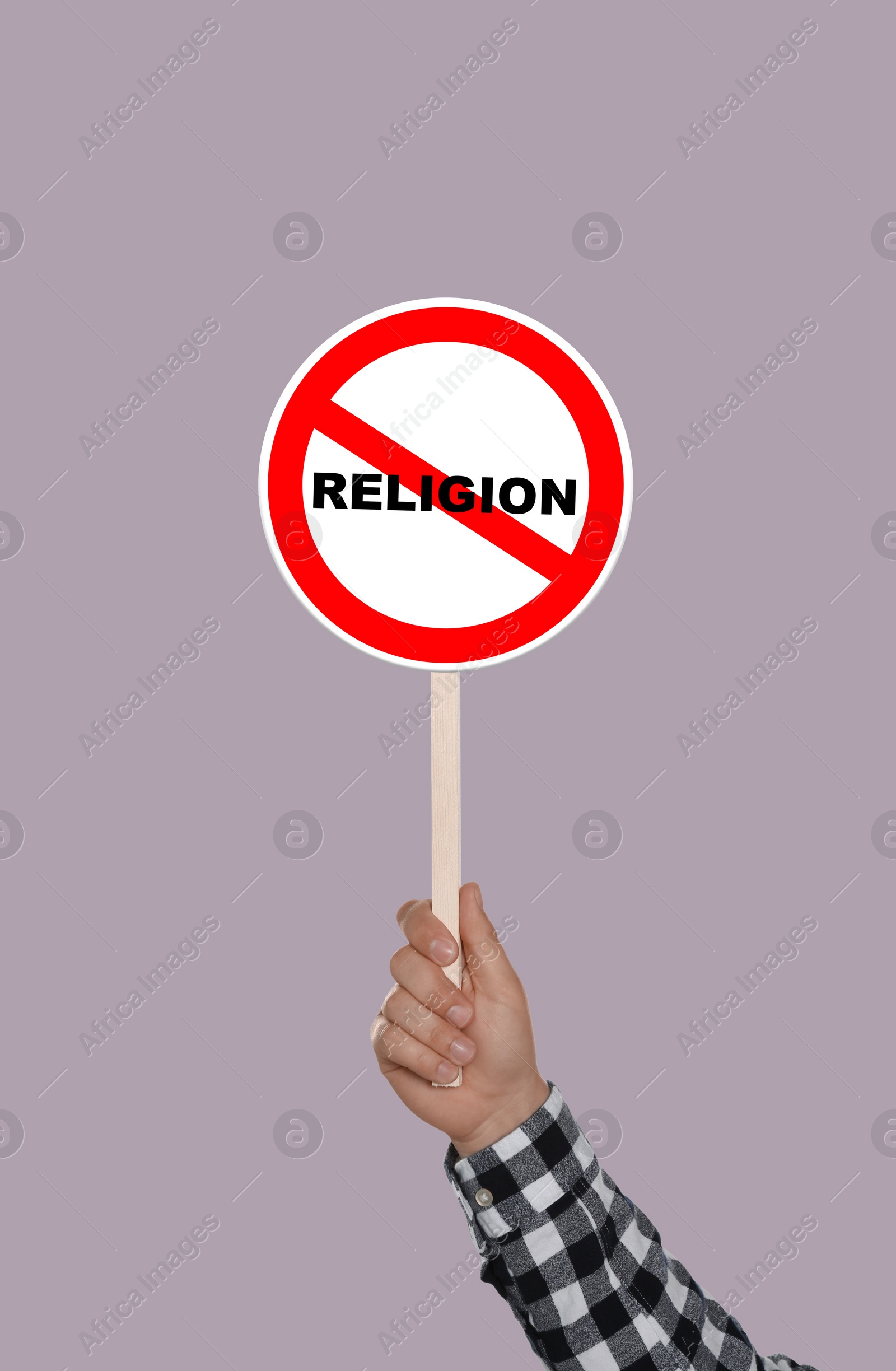 Image of Atheism concept. Man holding prohibition sign with crossed out word Religion on color background