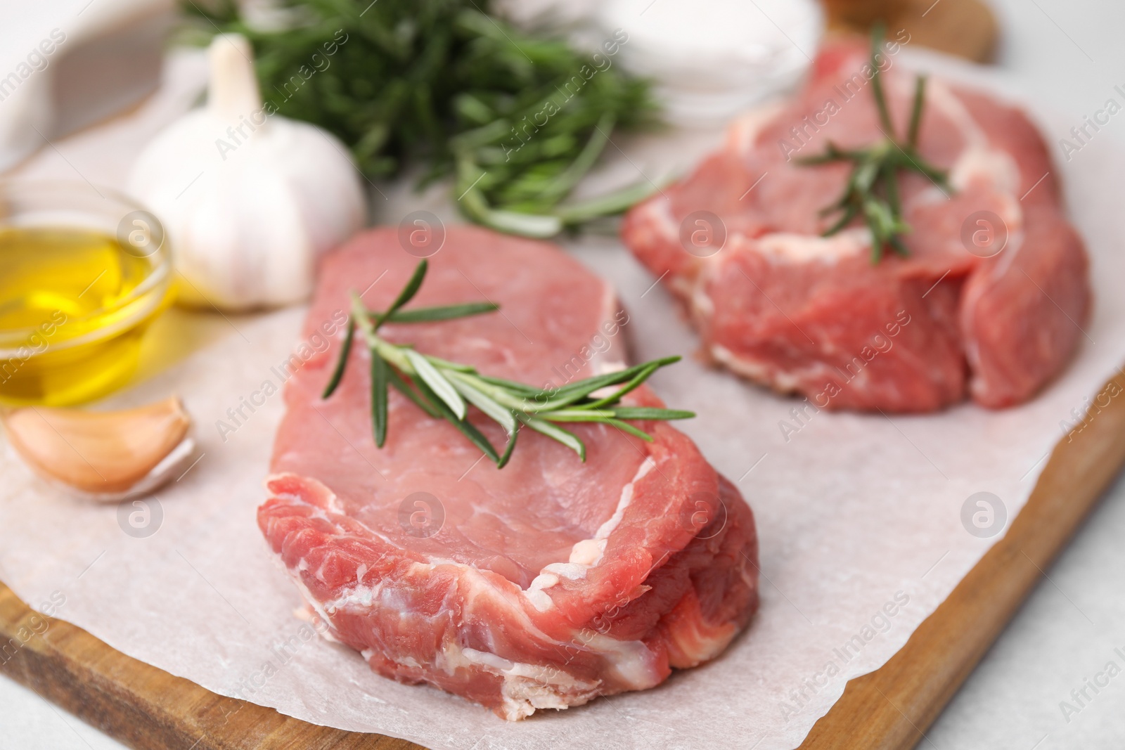 Photo of Fresh raw meat with rosemary on light grey table, closeup